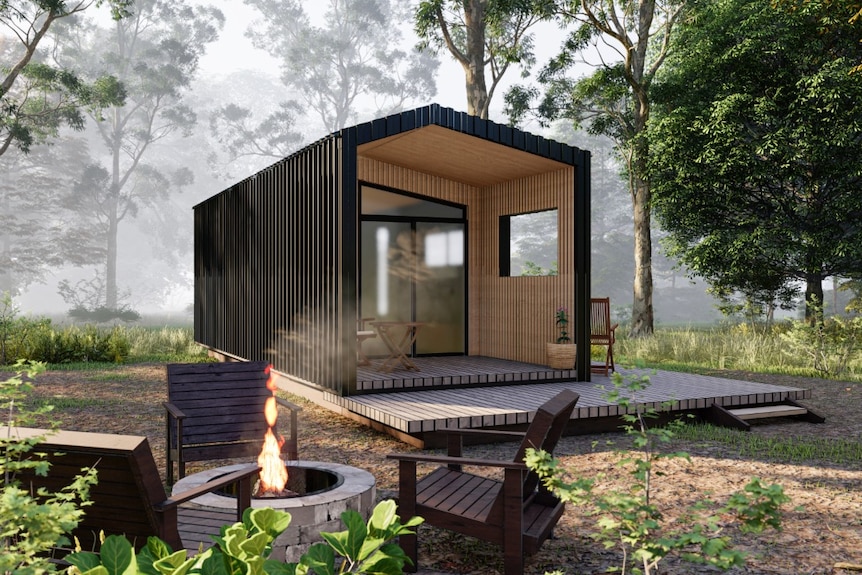 A black tiny home with a wooden entrance with outdoor living set in a forest.