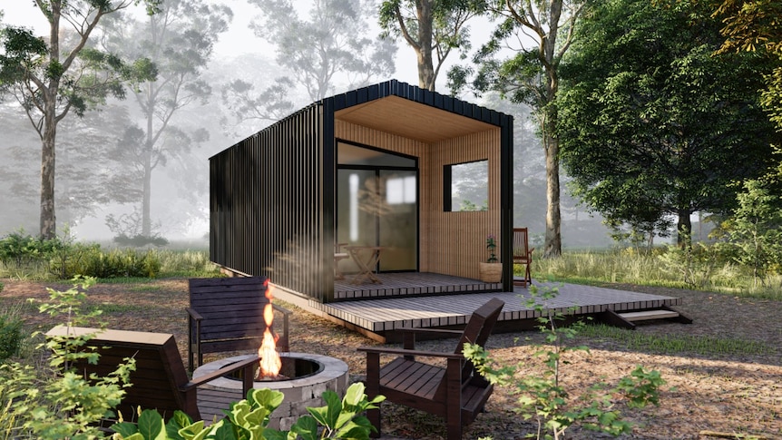 A black tiny home with a wooden entrance with outdoor living set in a forest.