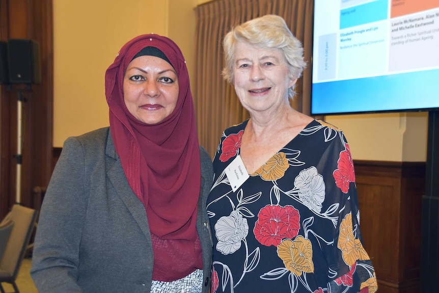 two women standing close and smiling at the camera