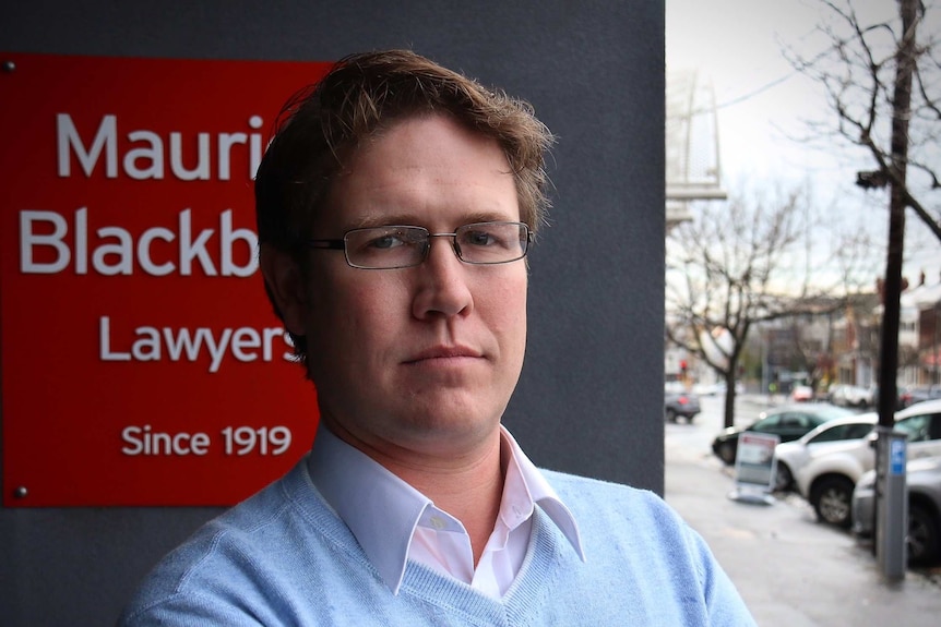 Sebastian Smith stands in front of a Maurice Blackburn office.