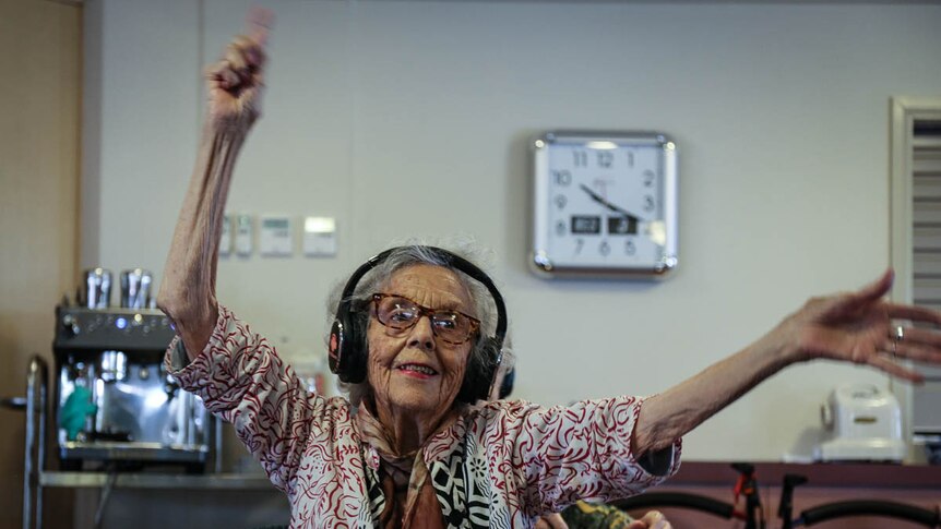 Woman with headphones on, waving hands in the air