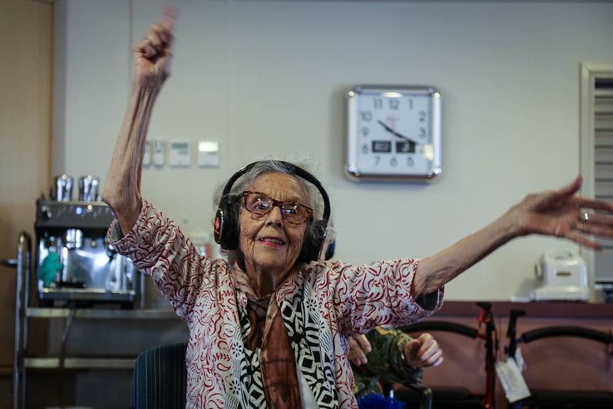 Woman with headphones on, waving hands in the air