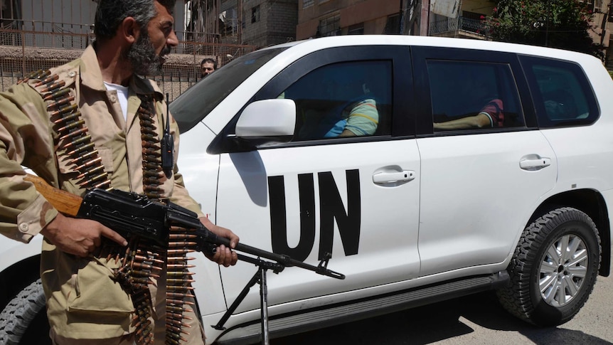 Free Syrian Army fighter escorts UN car