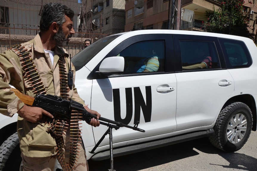 Free Syrian Army fighter escorts UN car