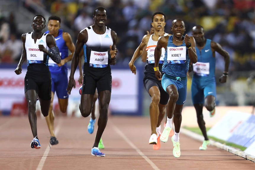 Male athletes run around a track during an international meet