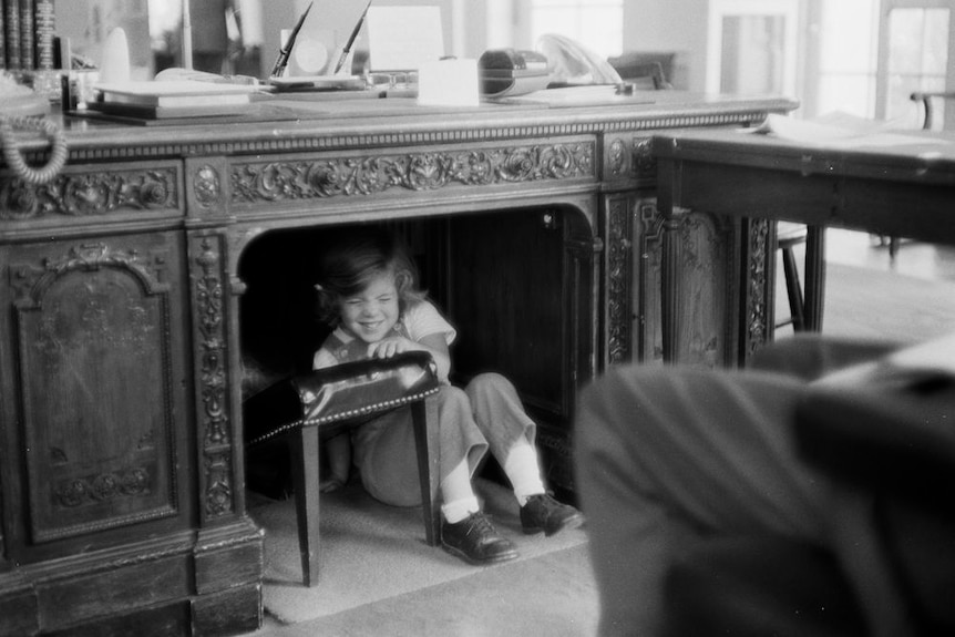 Little Caroline Kennedy hiding under the Resolute Desk 