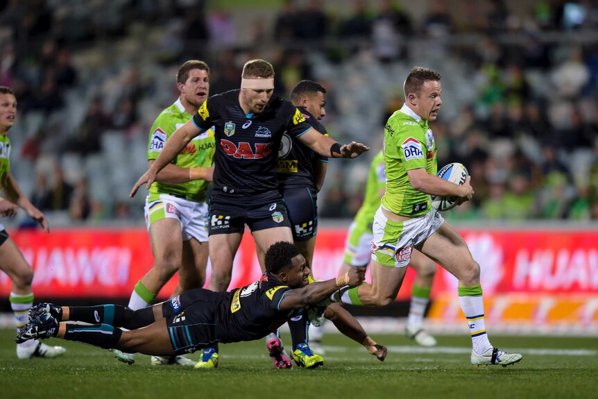 Sam Williams of Canberra is tackled by Penrith's James Segeyaro in round 25, 2015 in Canberra.