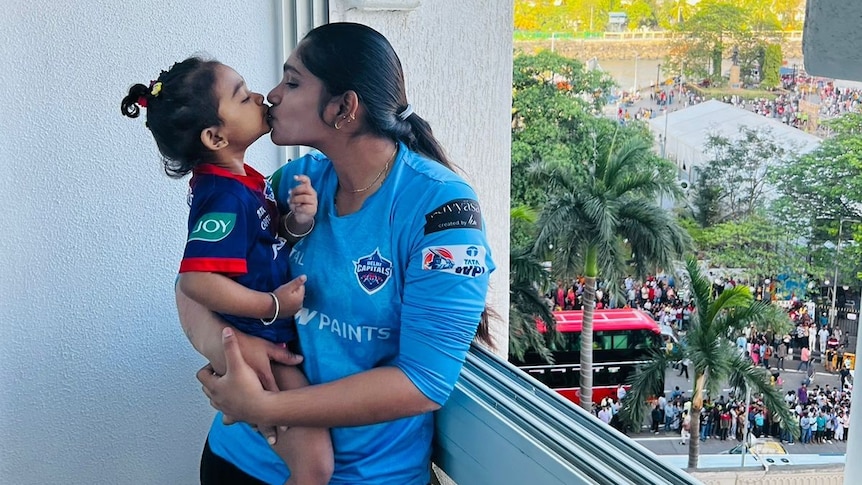 Sneha Deepthi holds her two year old daughter on a balcony and kisses her.