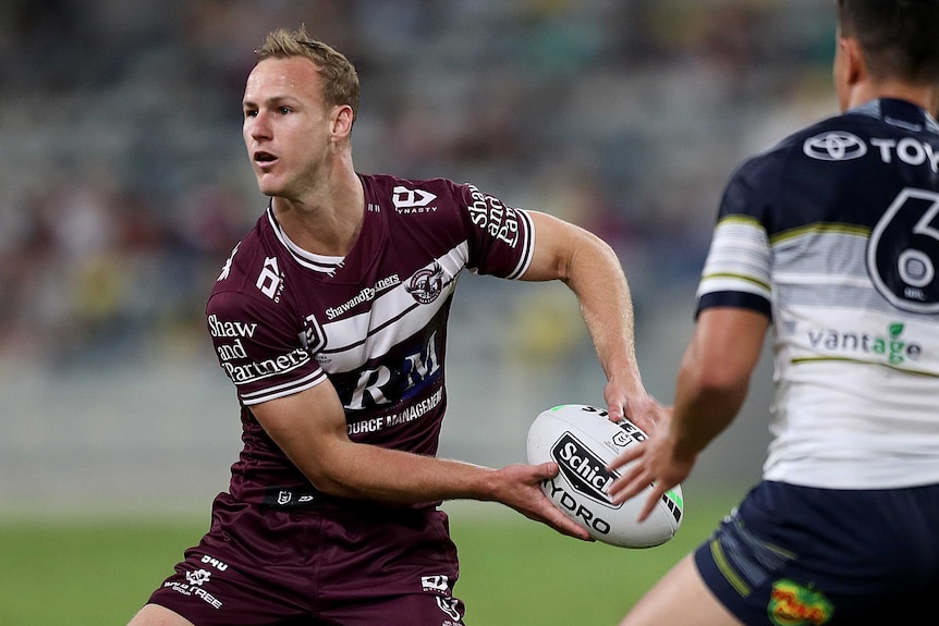 A Manly Sea Eagles NRL player prepares to pass the ball to his right against the North Queensland Cowboys.