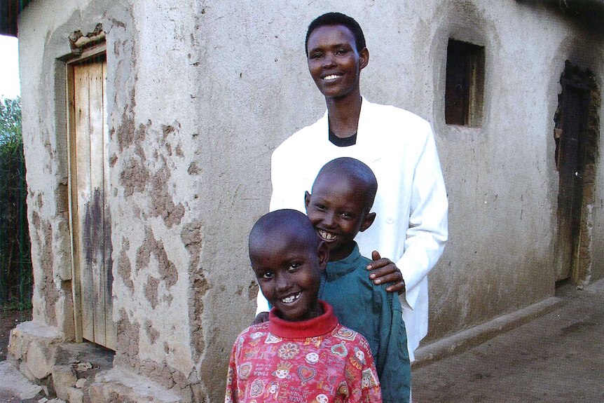 A Rwandan mother and her two children smile for a photo.