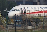 Workers inspect a Sichuan Airlines aircraft that made an emergency landing.