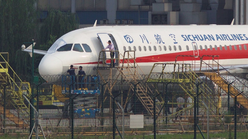 Workers inspect a Sichuan Airlines aircraft that made an emergency landing.