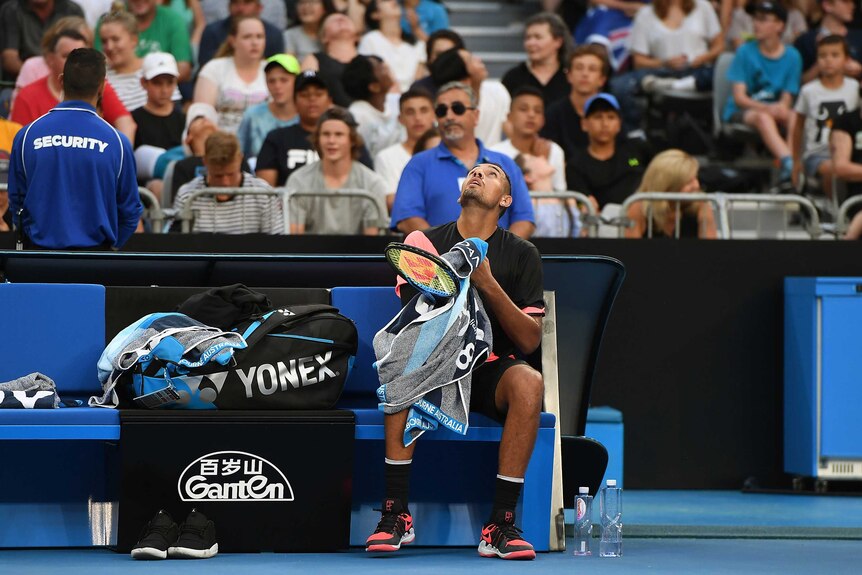 Nick Kyrgios looks to the sky as a helicopter hovers above Melbourne Park.