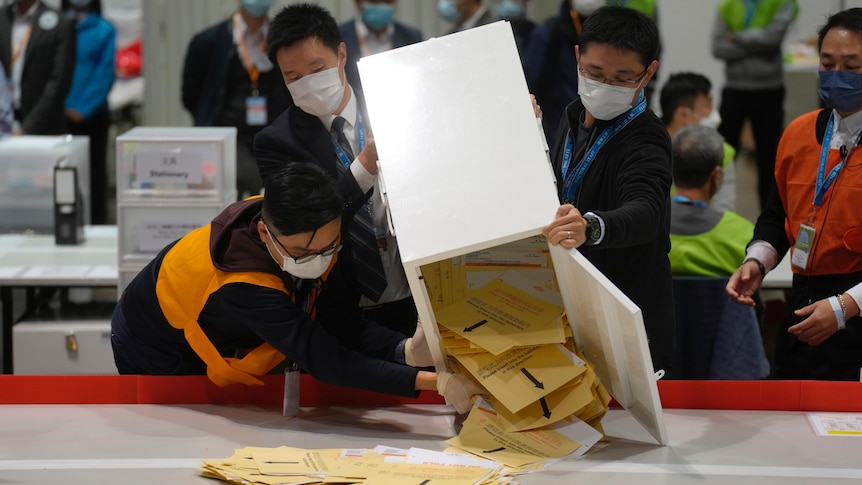 Election workers pour ballots out of a box to be counted. 