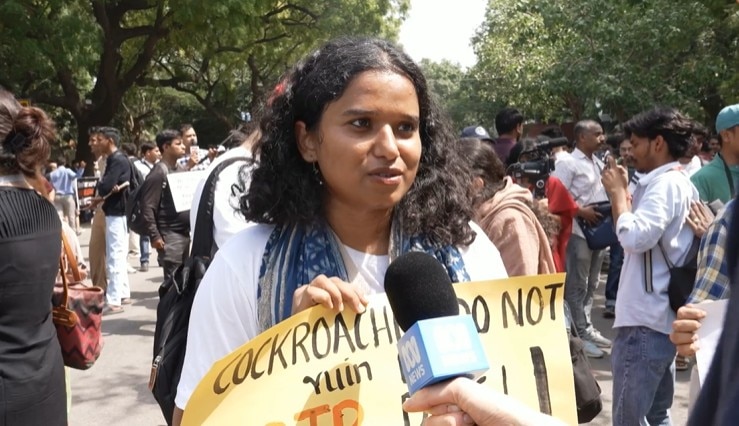 A girl stands with a poster calling for education reform