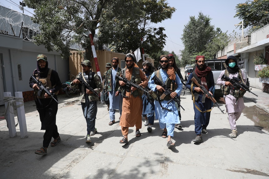 Taliban fighters patrol in a line with their weapons after they took over Kabul, August 2021.