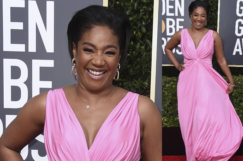 Tiffany Haddish smiles for the camera wearing a bright pink floor length dress.