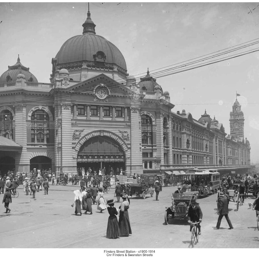 A black and white image of a domed gothic building with people milling about in front