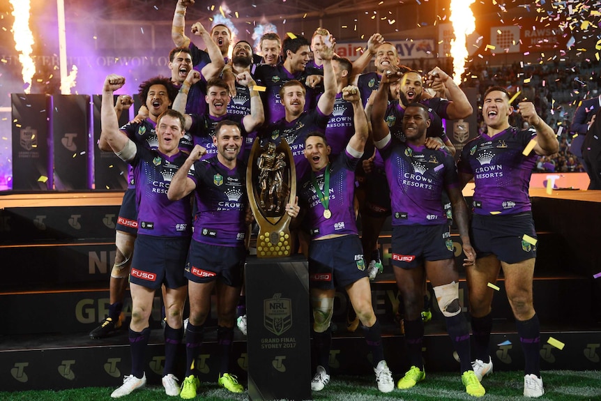 Melbourne Storm players pose with the NRL premiership trophy.