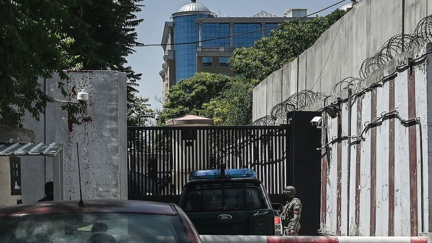 A security guard checks cars at the heavily fortified and monitored entrance to the now-closed embassy compound in Kabul