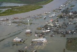 Buildings and homes sit in flooded waters surrounded by debris.