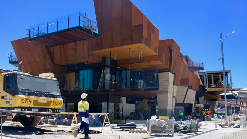 A construction worker in high-viz outside the partially-finished Yagan Square building in Perth's CBD.