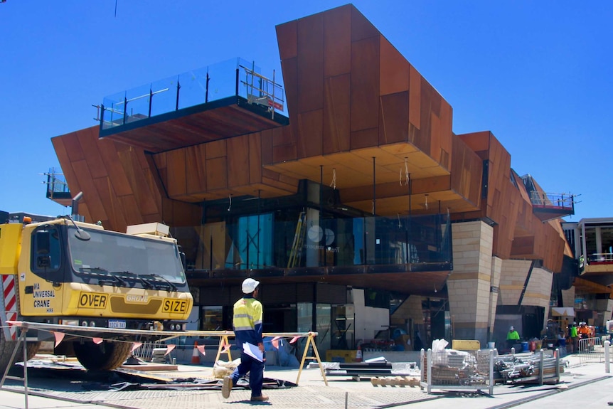 A construction worker in high-viz outside the partially-finished Yagan Square building in Perth's CBD.