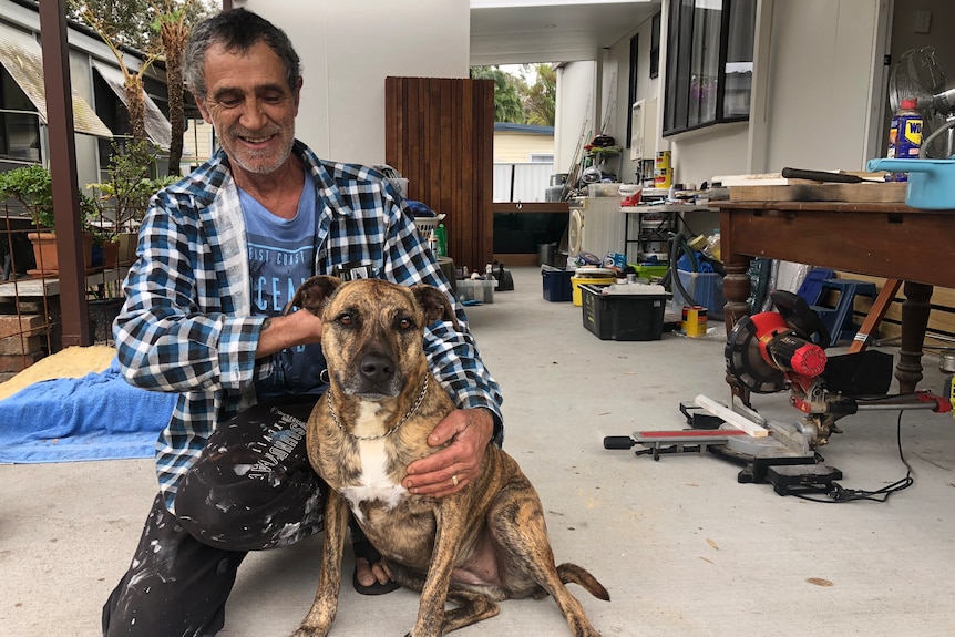 Holiday park resident Fran Ellul patting his dog under the carport