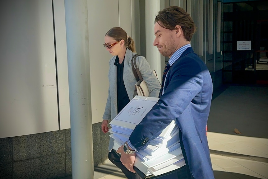 A woman walks with a lawyer carrying document.