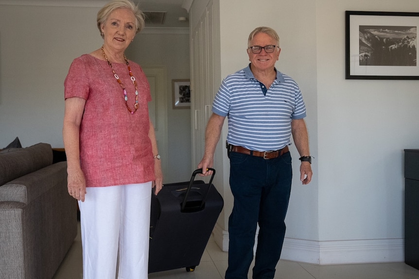 A man and a woman carrying luggage. 