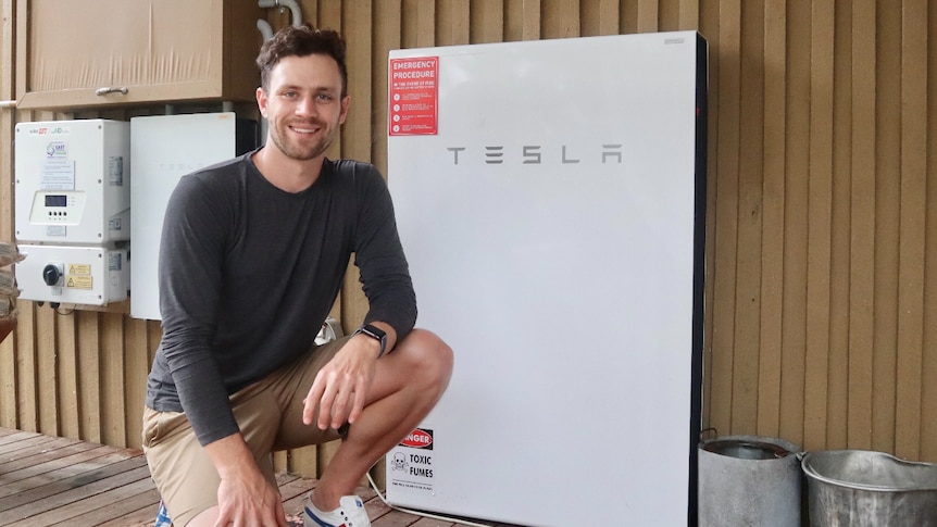 a man smiling next to a big storage battery
