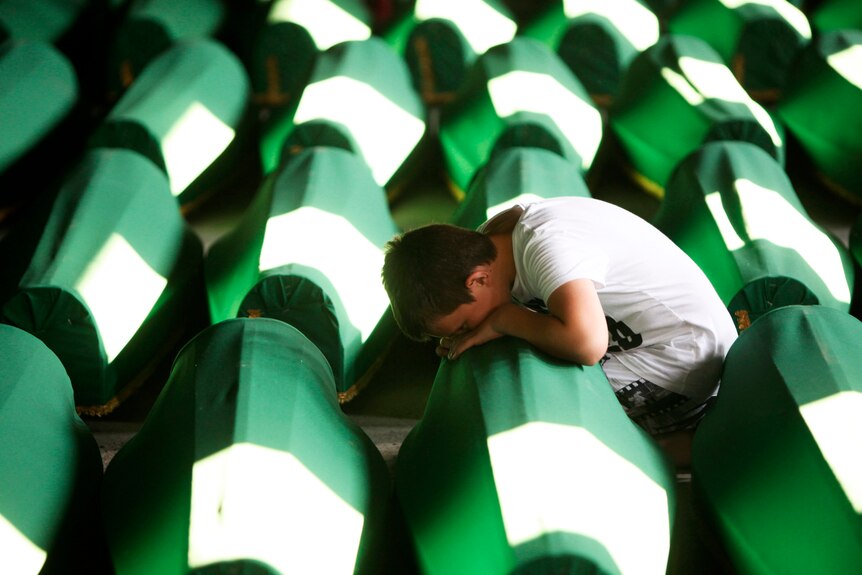 A Bosnian Muslim boy cries beside coffins prepared for a mass burial at the Memorial Centre in Potocari, near Srebrenica.