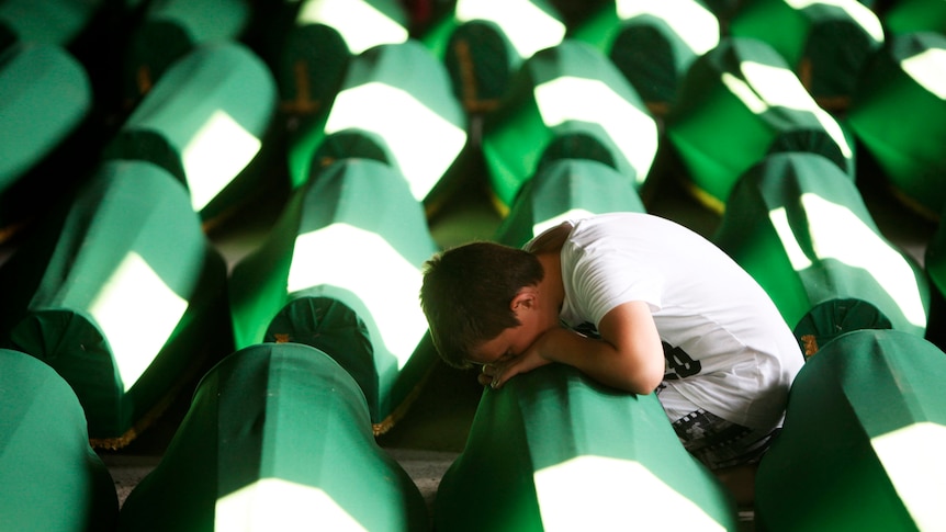A Bosnian Muslim boy cries beside coffins prepared for a mass burial at the Memorial Centre in Potocari, near Srebrenica.