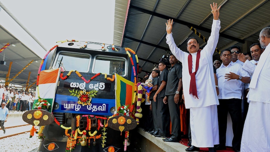 Sri Lankan president Mahinda Rajapakse raises both hands to acknowledge cheers