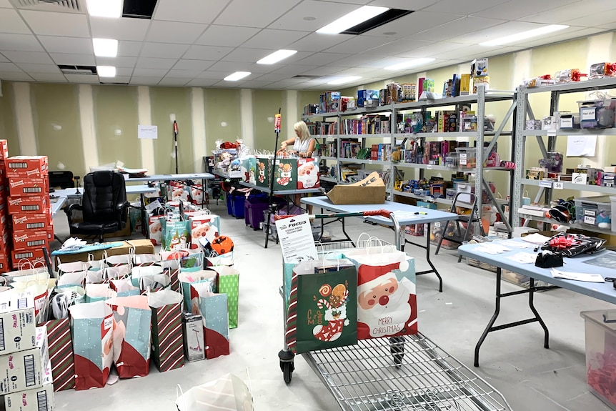 Woman working in warehouse full of Christmas gifts on shelves and on tables