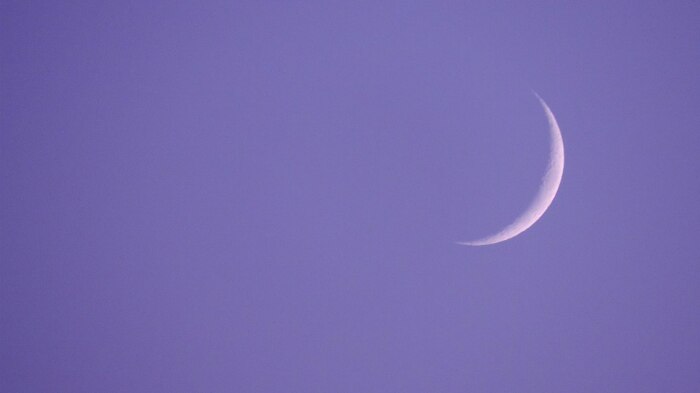 A crescent moon in a purple sky