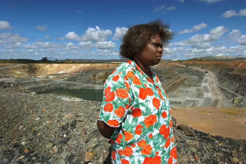 Yvonne Maragarula stands in front of an open cut mine