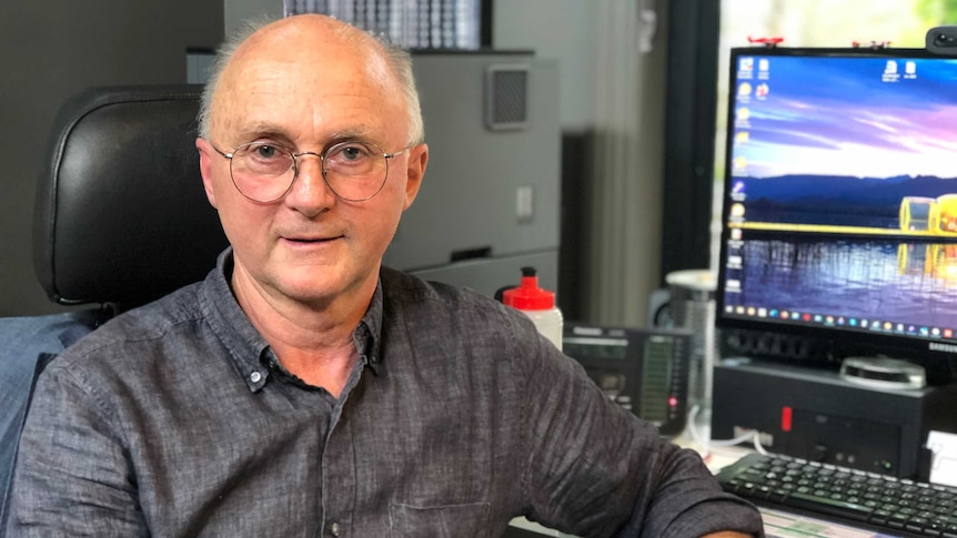 Portrait of Dr Jim Berryman sitting in front of his compute in his office