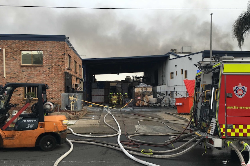 A fire crew in a cherry picker spraying water onto the factory