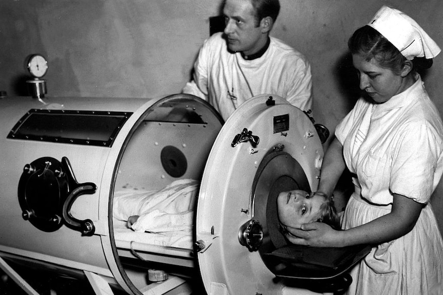 A young boy in Germany is prepared to be placed in an iron lung with two nurses around him