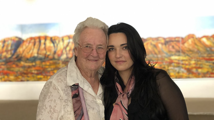 A younger woman with black hair poses alongside an older woman.