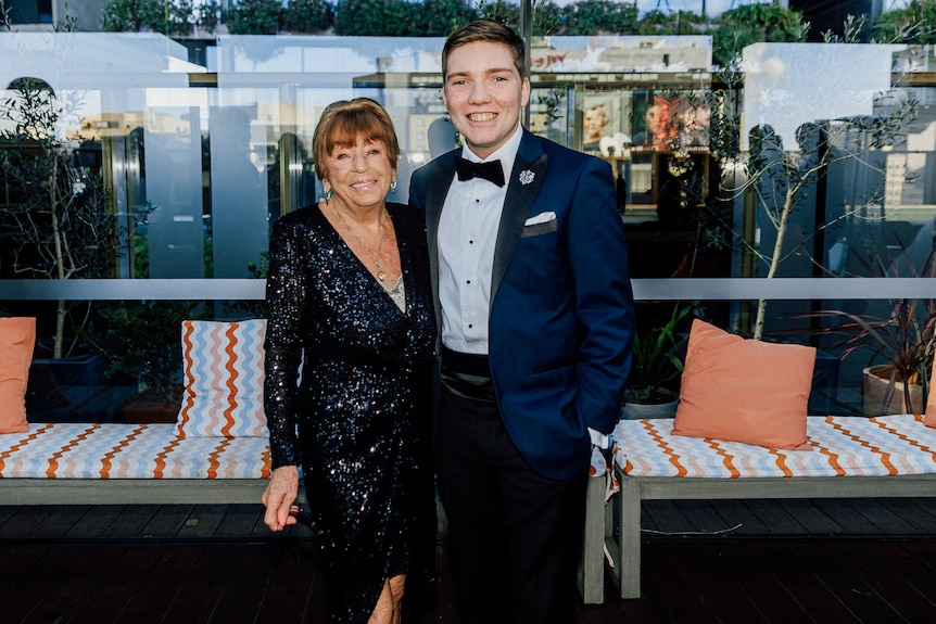 Aranka on the left wearing a sequined black dress stands next to Miles who is in a dark blue suit with a bow tie