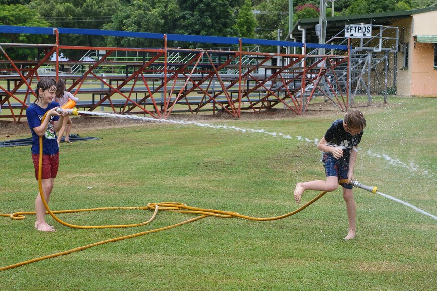 a young boy hoses another at the town showgrounds