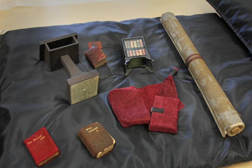 Tiny books and manuscripts on a small black pillow.