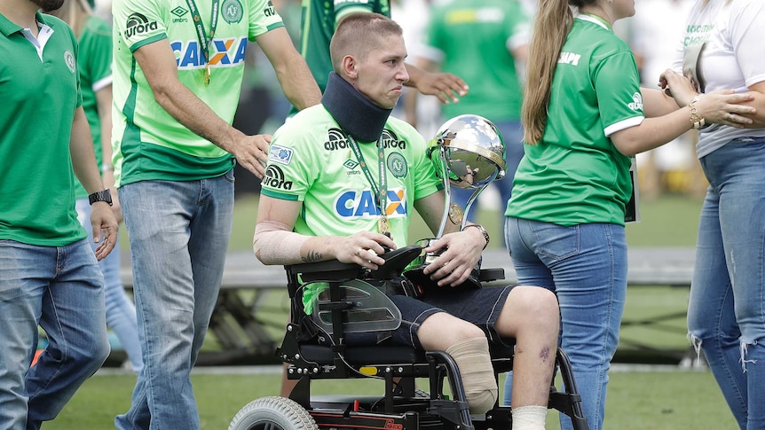 Chapecoense goalkeeper Follmann, one of the three players that survived the air crash almost two months ago, is wheeled on the pitch as he carries the Sudamericana trophy