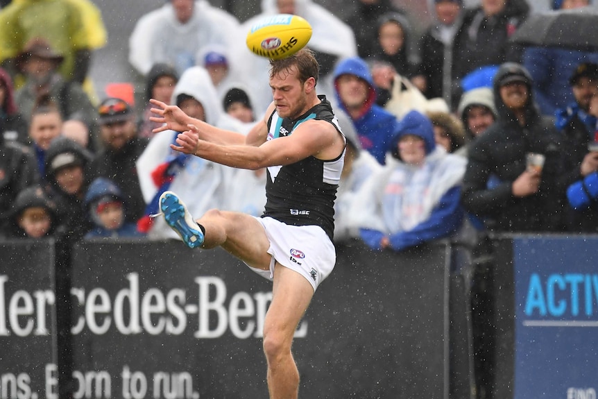 Jack Watts attempts to kick the ball, which is positioned near his forehead.