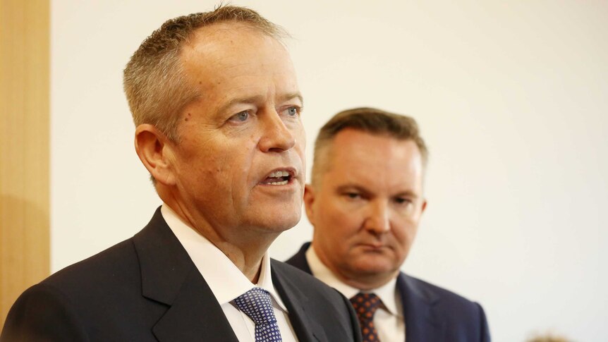 Bill Shorten addresses someone out of the line of sight of the camera, with Chris Bowen behind.