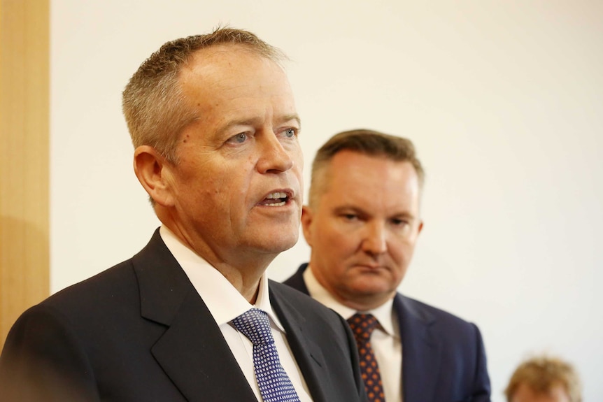 Bill Shorten addresses someone out of the line of sight of the camera, with Chris Bowen behind.