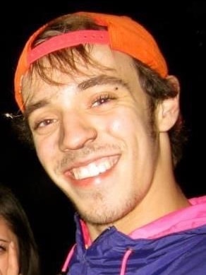 A young man with a baseball cap smiles