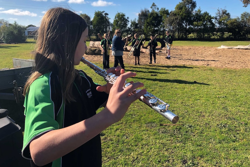 A female student plays the flute on the school oval